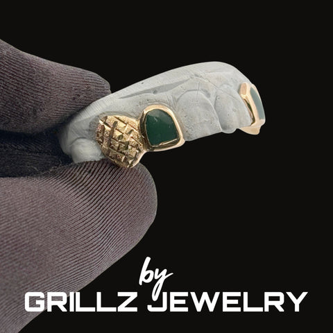 Jewelry with green stone and gold accents on a dark background, featuring 'GRILLZ JEWELRY' branding.