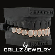Black grill with rose gold and silver teeth on a black background, branded as Grillz Jewelry.