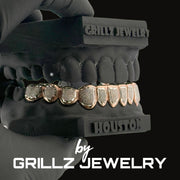 Grillz jewelry set on a black dentures model with 'Grillz Jewelry' branding.