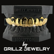 Diamond-studded grillz held by a gloved hand with 'Grillz Jewelry' branding.
