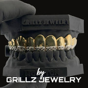 Silver grillz jewelry held by a gloved hand with 'Grillz Jewelry' branding.