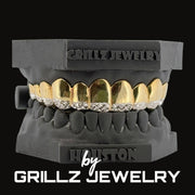 Black grill with gold and diamond accents on a black stand, branded 'Grillz Jewelry'.