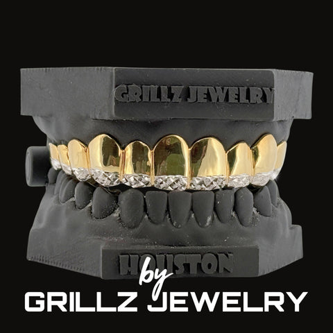 Black grill with gold and diamond accents on a black stand, branded 'Grillz Jewelry'.