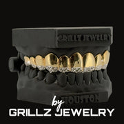 Black grill with gold and diamond accents on a black background, featuring 'Grillz Jewelry' branding.