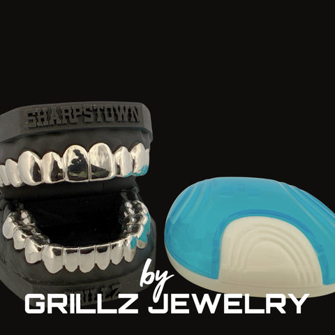 Grillz jewelry set with clear teeth and black frame, displayed against a black background.