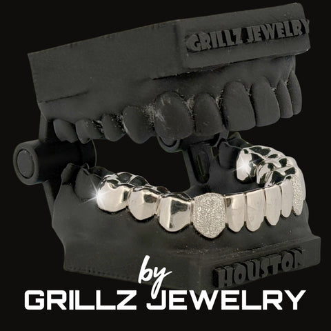 Silver grillz on a black stand with 'Grillz Jewelry' branding.