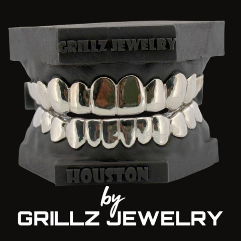 Silver grillz on a black stand with 'Grillz Jewelry' branding.
