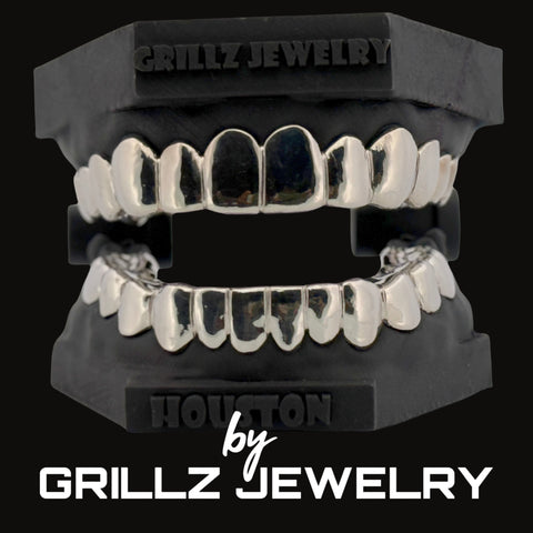 Silver grillz on a black stand with 'Grillz Jewelry' branding.