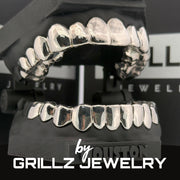 Silver grillz on a stand with 'Grillz Jewelry' branding in the background