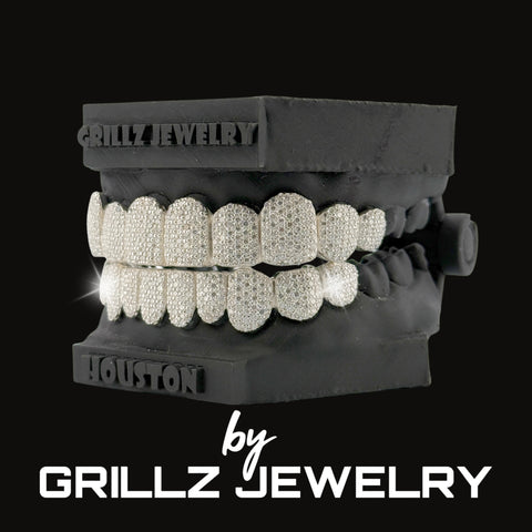 Diamond-studded grill on a black stand with 'Grillz Jewelry' branding.