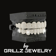 Diamond-studded grill on a black stand with 'Grillz Jewelry' branding.
