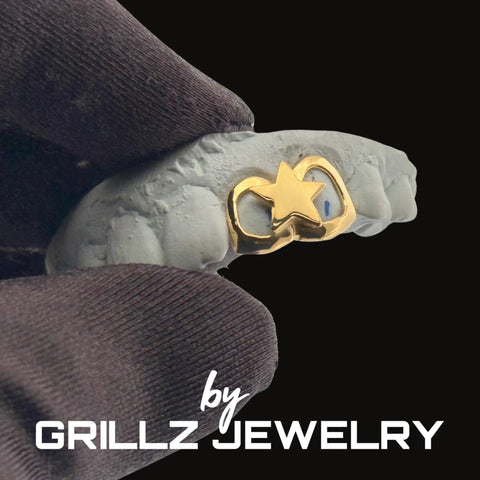 Gold ring with star design on a gray hand, branded 'Grillz Jewelry'.