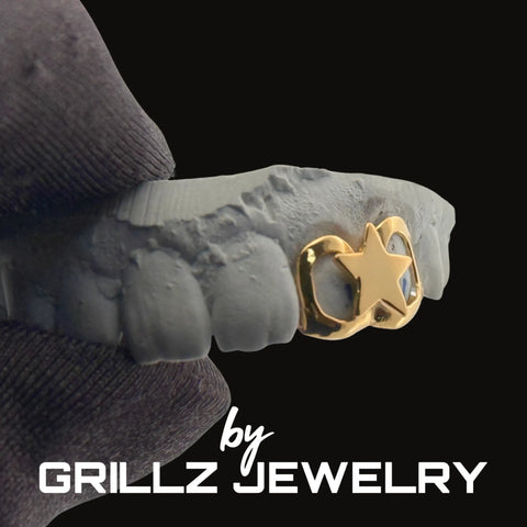 Gold grill with star design on a gray background, branded as Grillz Jewelry.