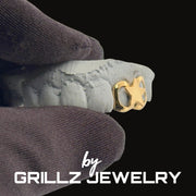 Gold grill on a white foam block with 'Grillz Jewelry' branding.