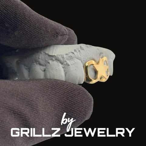 Gold grill on a white foam block with 'Grillz Jewelry' branding.