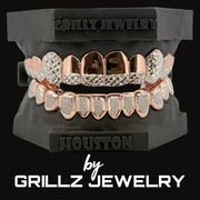 Rose gold and silver grillz on a black stand with 'Grillz Jewelry' branding.