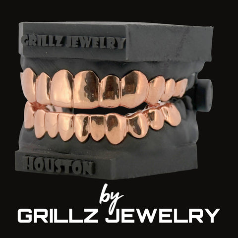 Rose gold grillz on a black stand with 'Grillz Jewelry' branding.