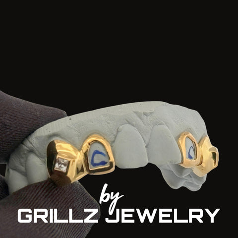 Gold grillz with blue stones on a hand, branded 'Grillz Jewelry'.