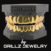 Gold grillz on a black stand with 'Grillz Jewelry' branding.