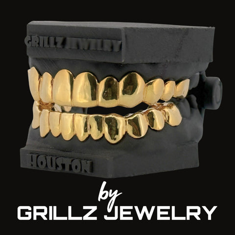 Gold grillz on a black stand with 'Grillz Jewelry' branding.