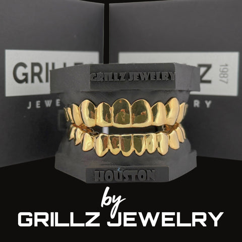 Gold grillz on a black stand with 'Grillz Jewelry' branding in the background.
