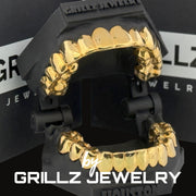 Gold grillz on a black stand with 'Grillz Jewelry' branding.